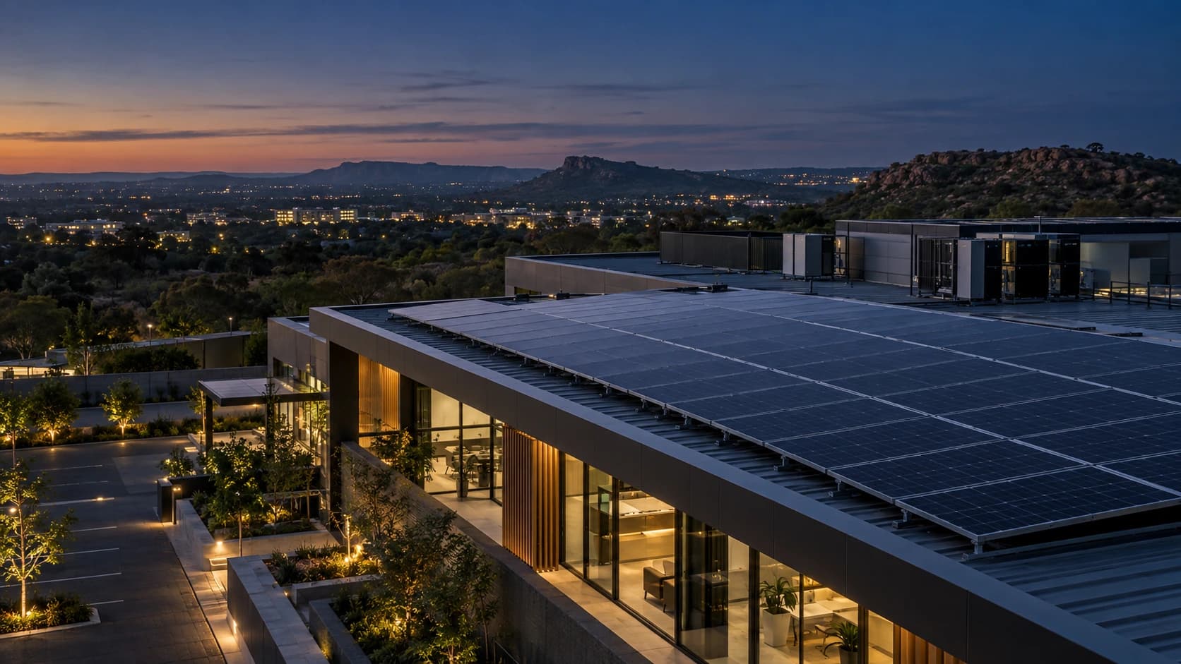 Modern South African commercial building with a large rooftop solar installation at blue hour