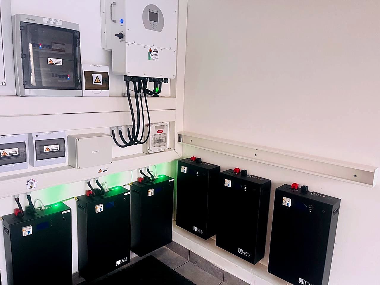 Bank of four lithium batteries with status lights, wired to a Sunsynk inverter
