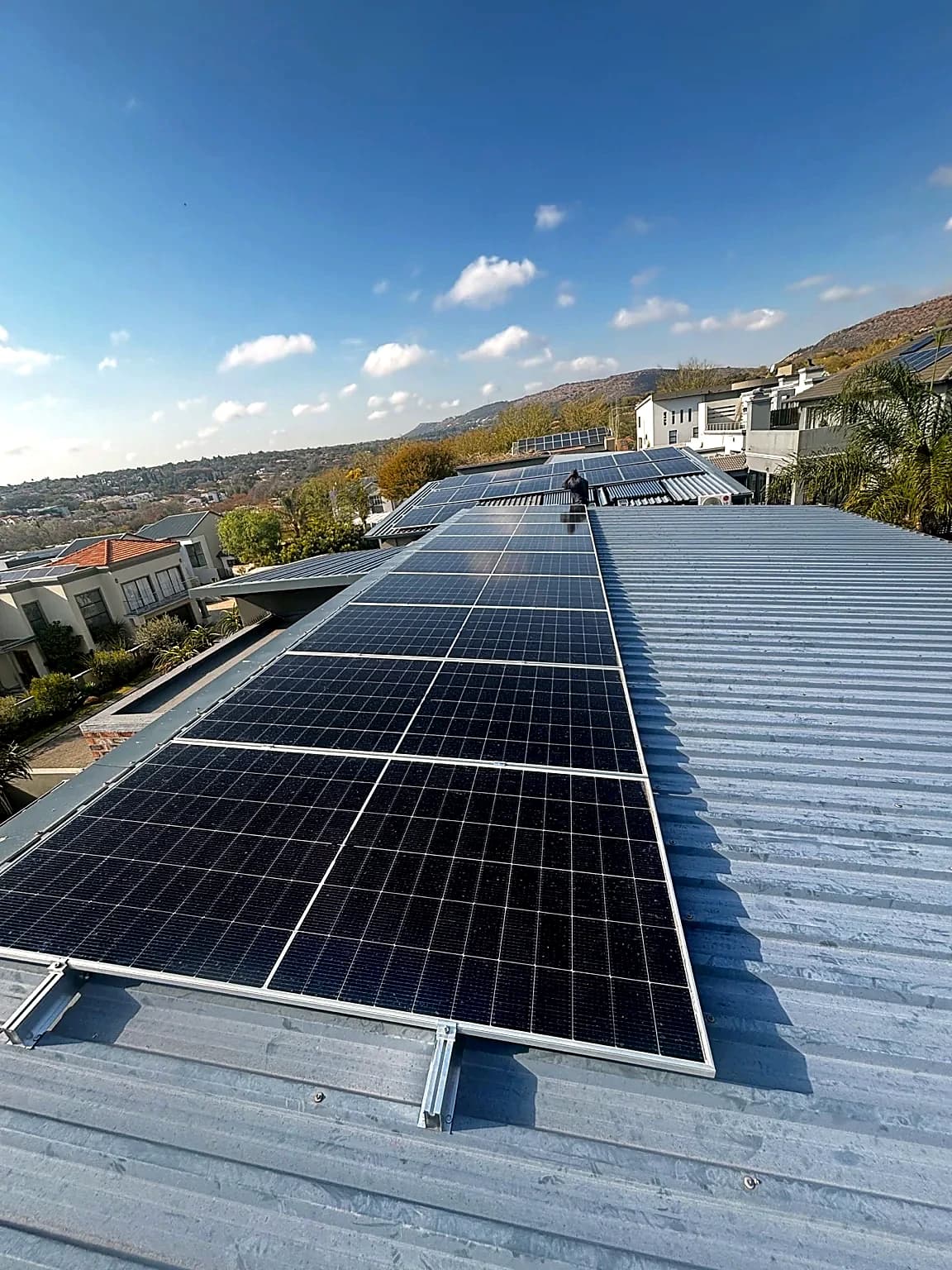 Rooftop solar panel array on a commercial building under a clear sky