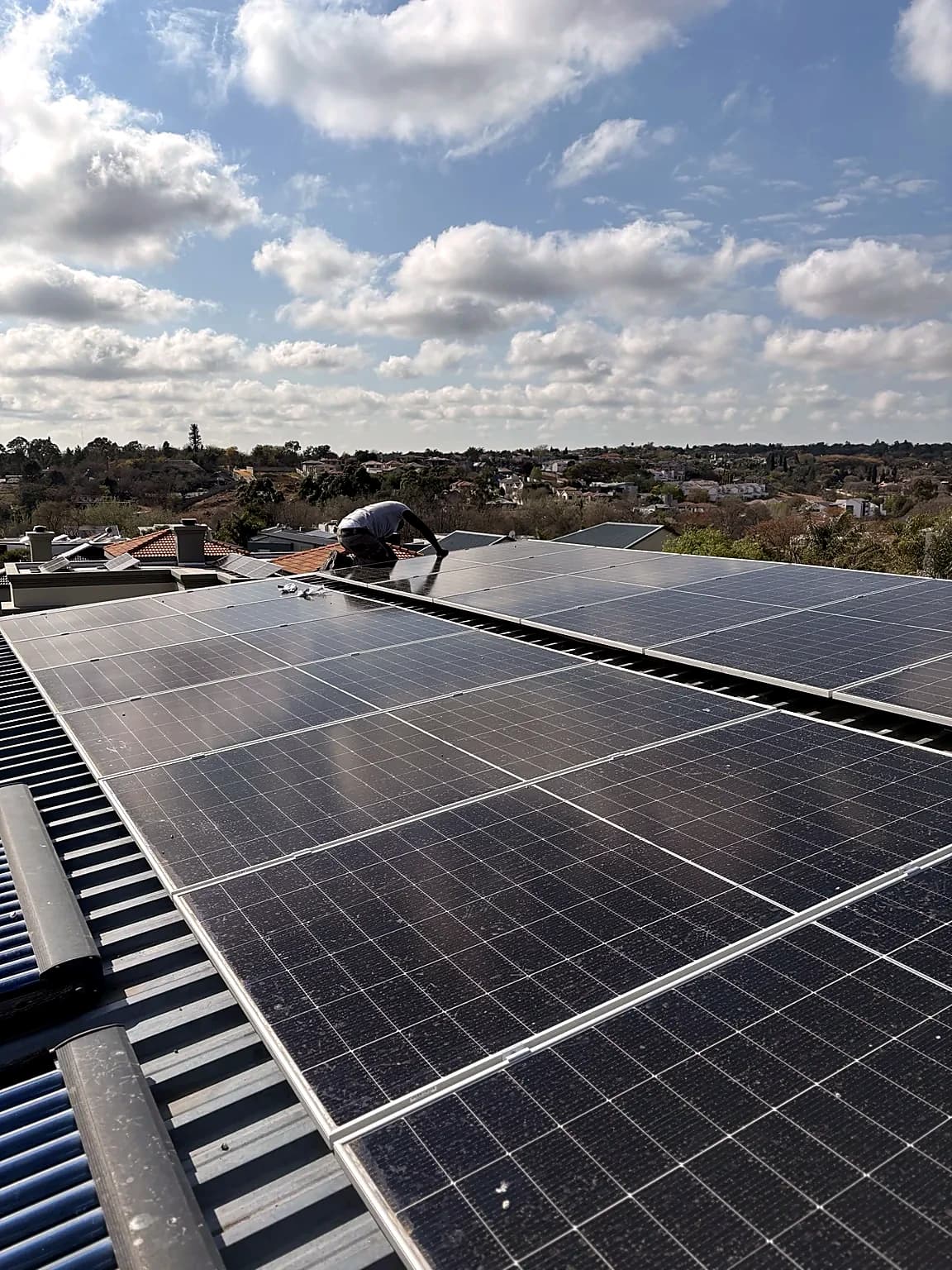 Solar panels installed on a roof overlooking a suburb